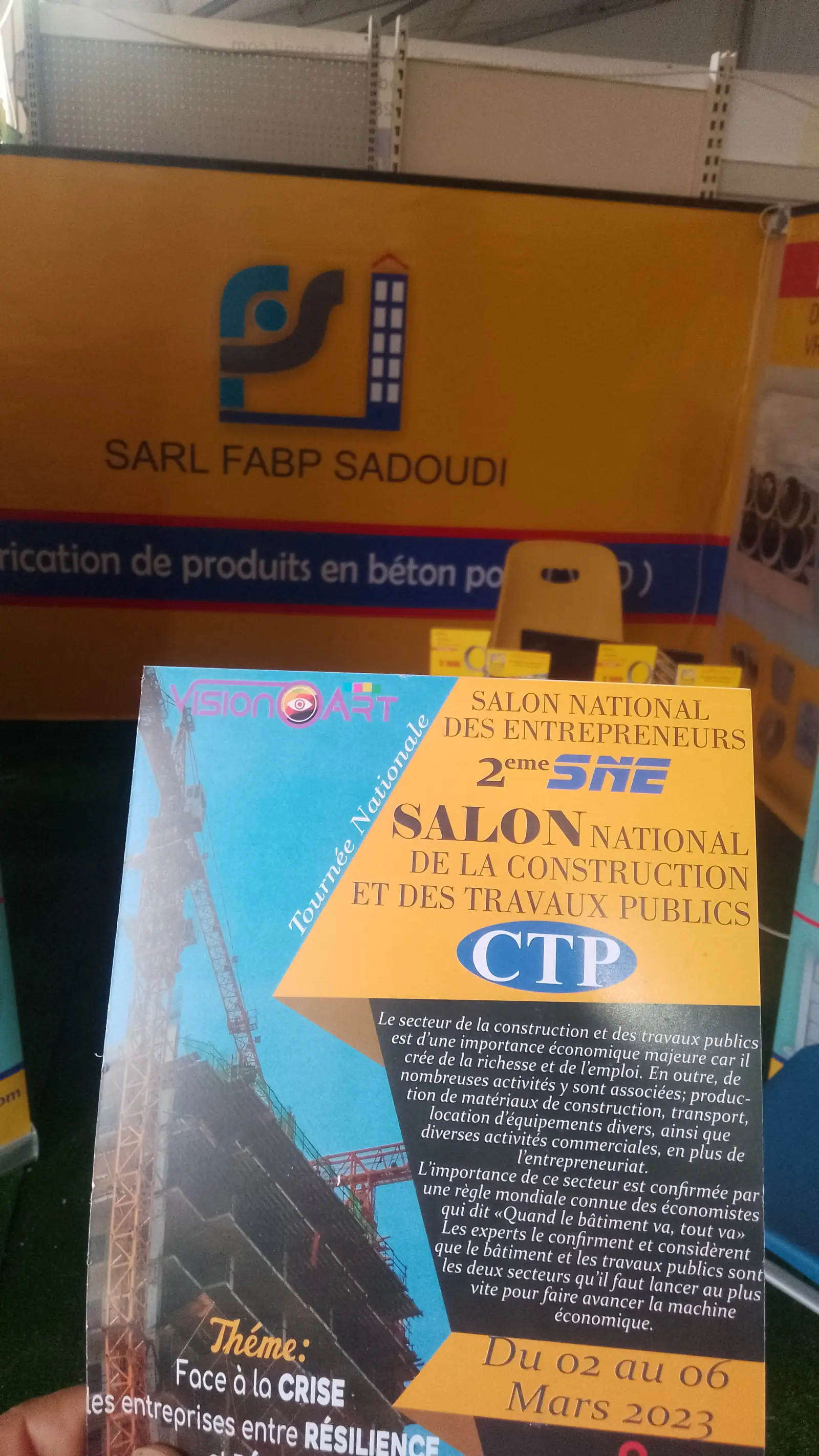 Programme du 2ᵉ Salon national de la construction et des travaux publics devant le stand FABP Sadoudi